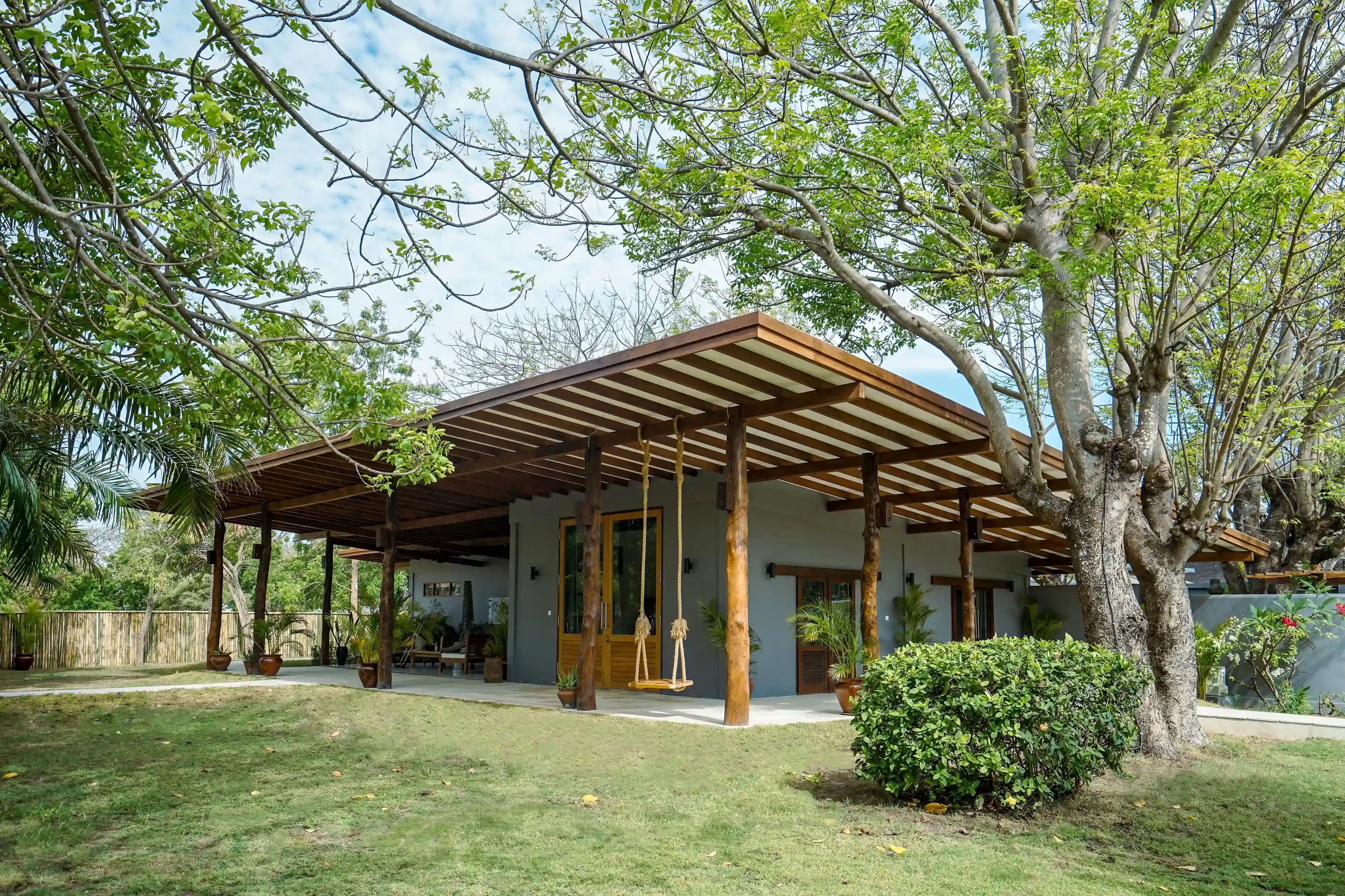 Exterior of the 2 Bedroom Family Villa, showing the large covered terrace and wooden swing, surrounded by a private garden