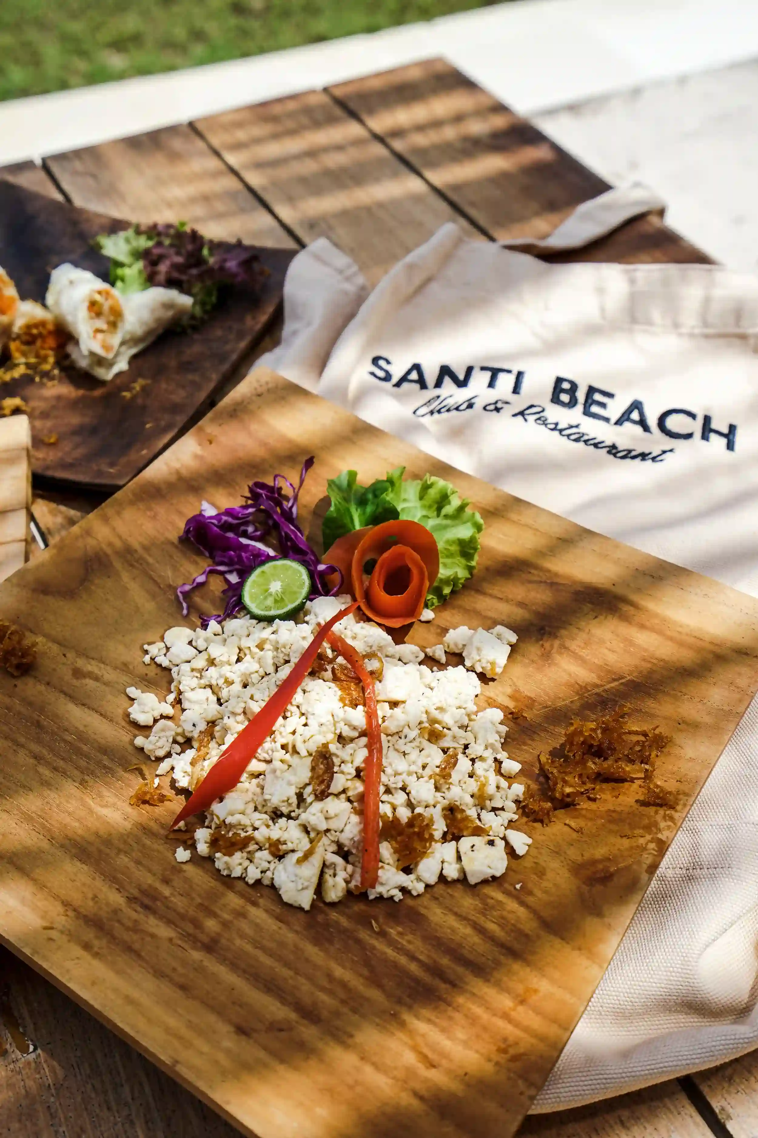 Close-up of fresh, raw ingredients for the Indonesian Cooking Class, including shallots, garlic, chilies, galangal, and vegetables, displayed in wooden bowls on a table hover