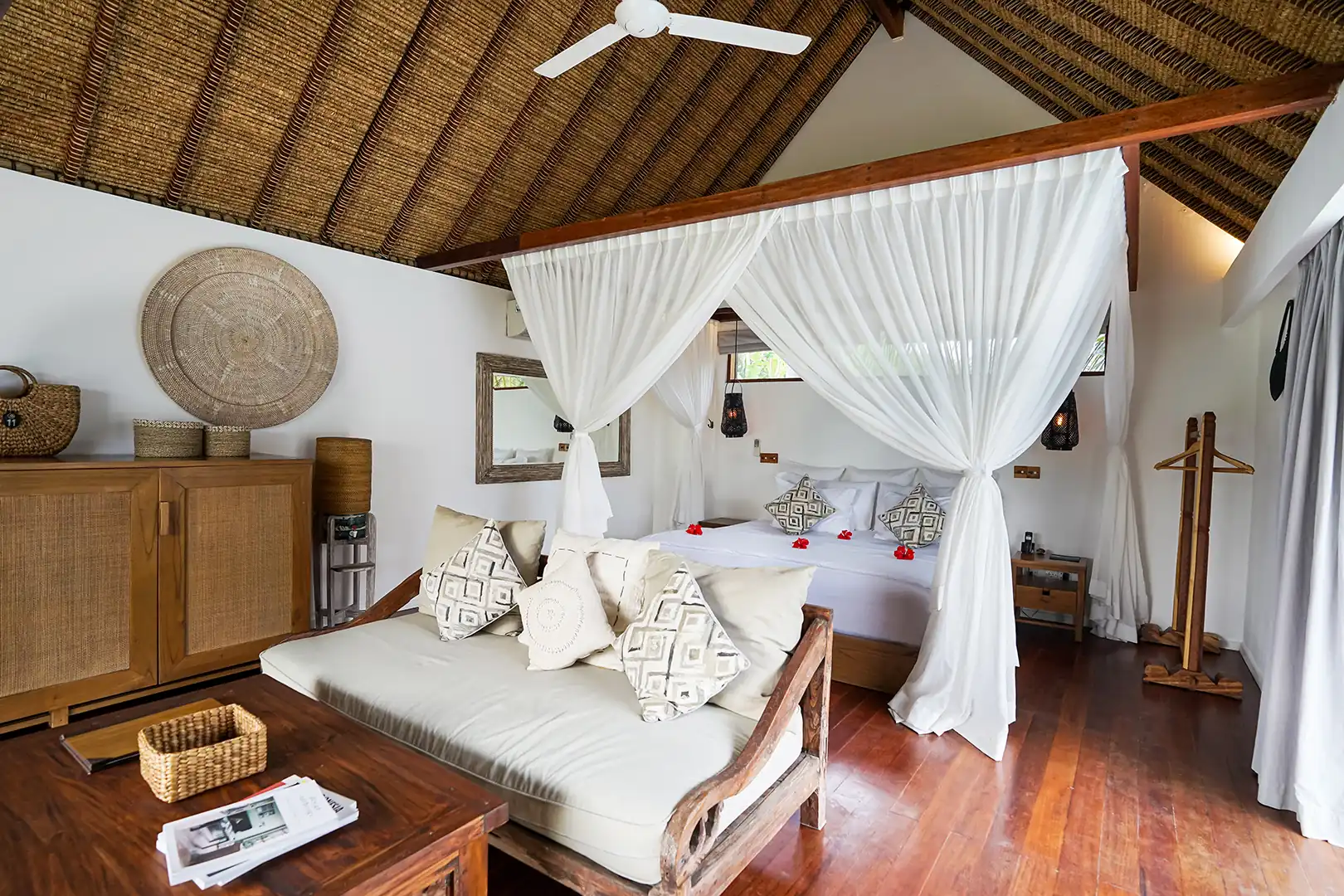 Exterior view of the Deluxe Private Pool Villa, showcasing the private lagoon-shaped pool, thatched-roof bungalow, and white stone sun terrace hover