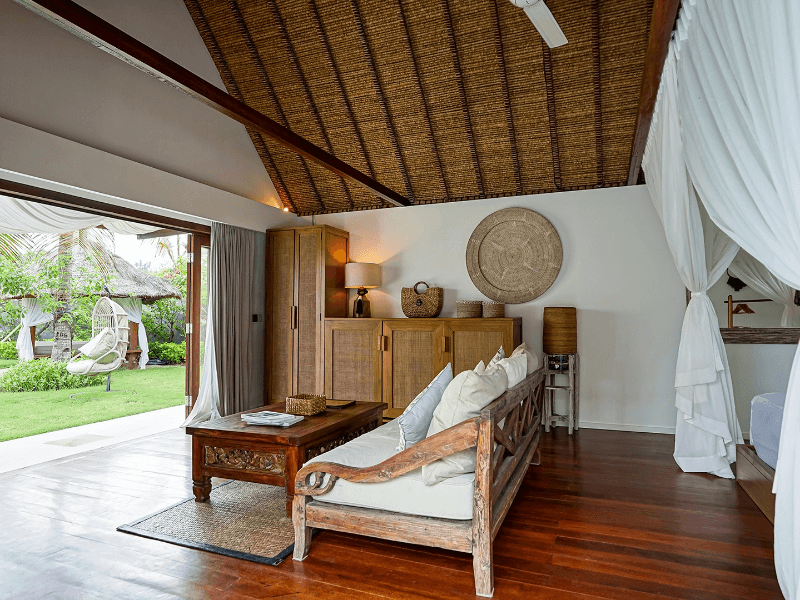 Luxurious interior of Deluxe Private Pool Villa at Pondok Santi Estate, Gili Trawangan, showcasing sofa and open glass doors to private garden.