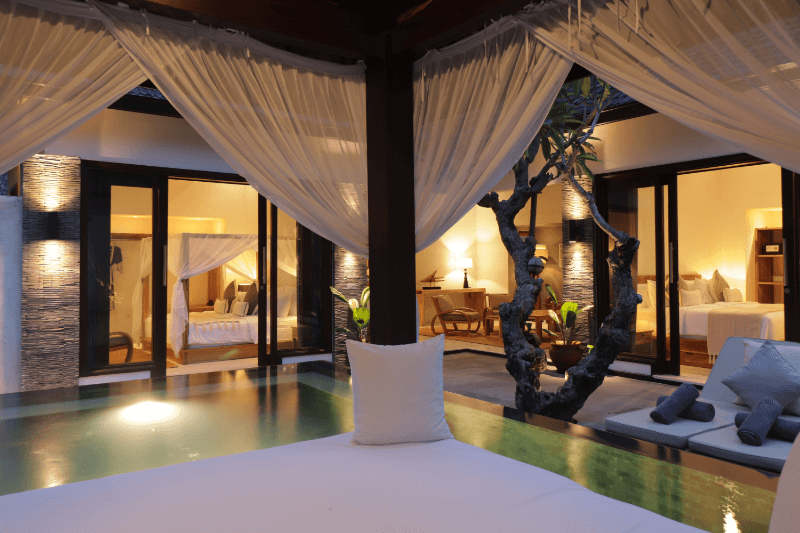 Evening ambiance at the 2-bedroom pool villa, Pondok Santi Estate, with a lit pool, bedrooms, and living room, creating a serene atmosphere.