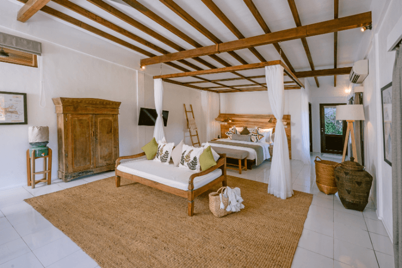 Spacious room in 2-bedroom family villa at Pondok Santi Estate, Gili Trawangan, featuring a bed and elegant sofa.