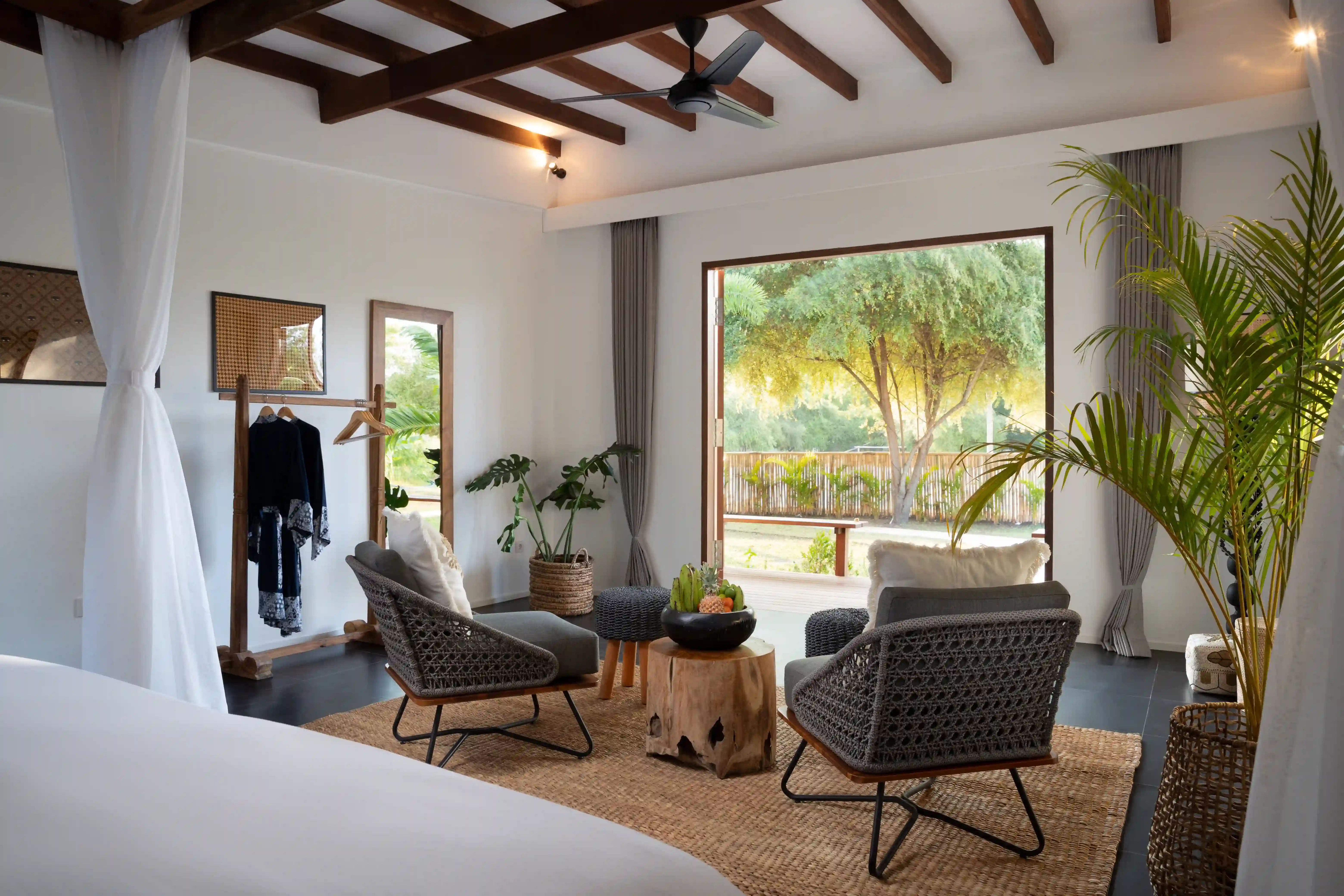 Interior of the Hill View Room, showing the tropical-style seating area, dark wood furniture, and large glass doors opening to the outdoor view
