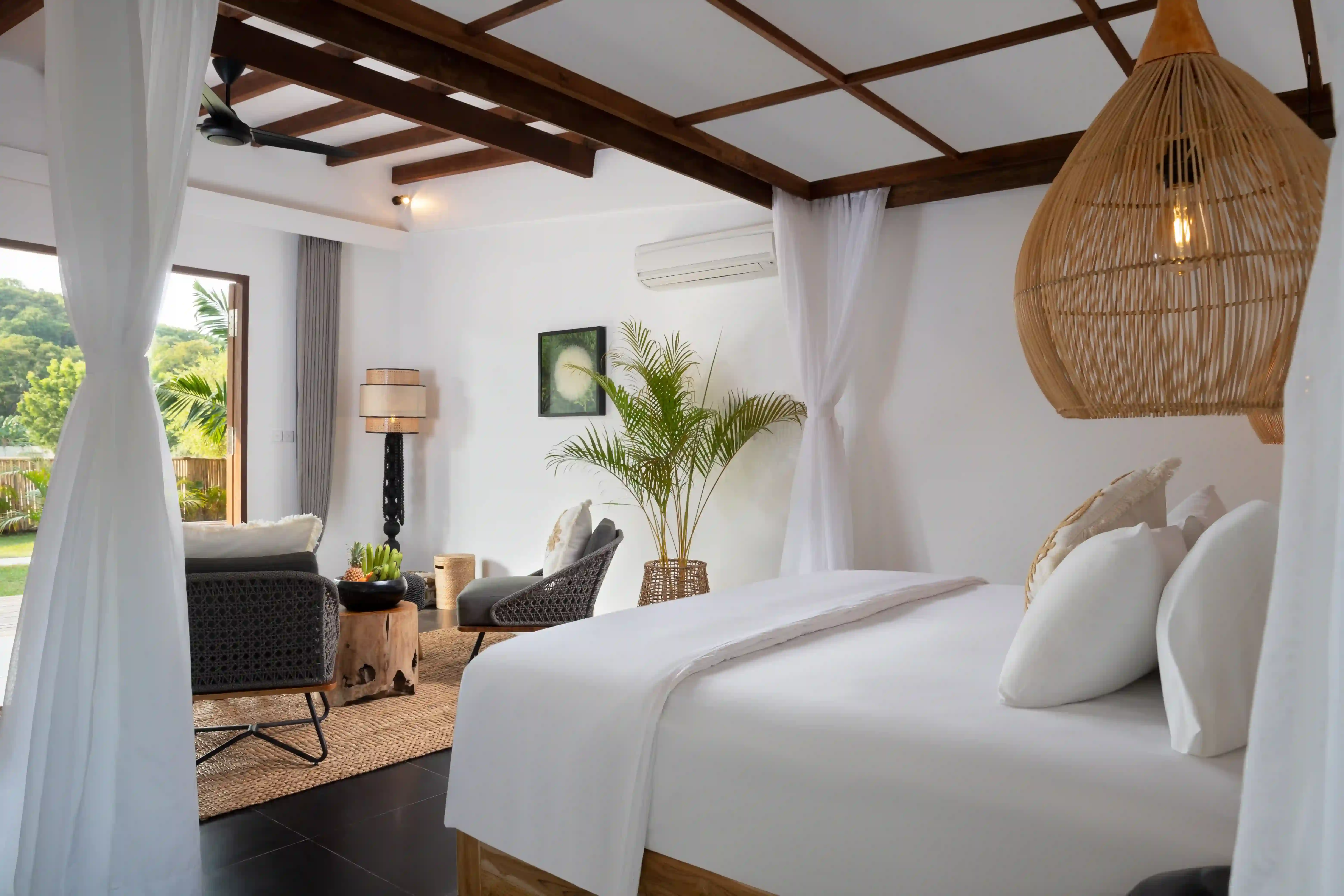 Interior of the Hill View Room, showing the tropical-style seating area, dark wood furniture, and large glass doors opening to the outdoor view hover