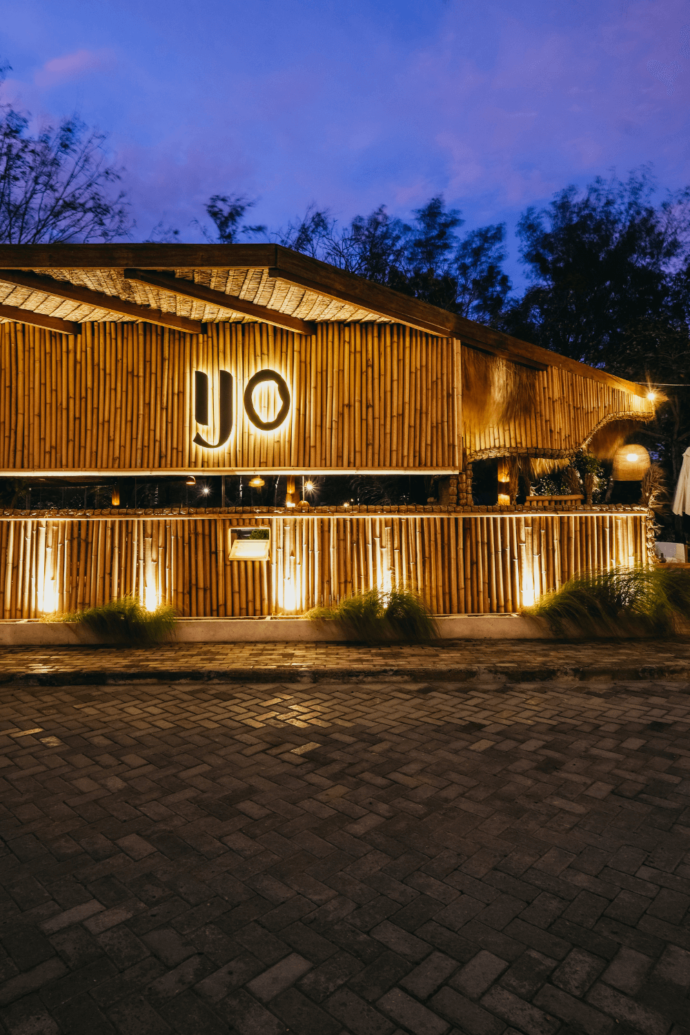 Entrance to Ijo restaurant at Pondok Santi Estate, beautifully illuminated with lights in the evening ambiance.