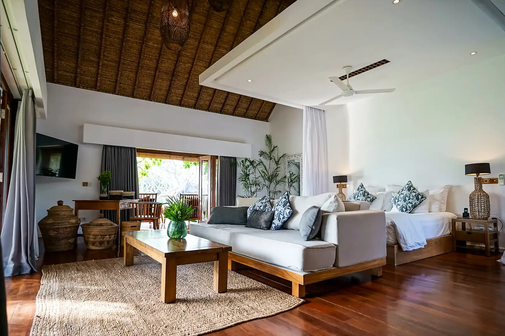 Exterior view of the Ocean View Villa's private wooden terrace with comfortable outdoor seating, seen framed by palm trees hover