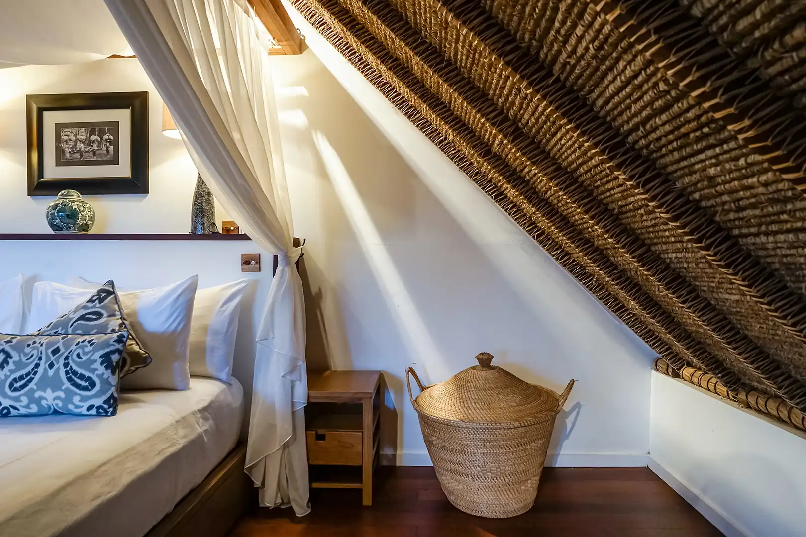 Master bedroom interior of the 2 Bedroom Ocean View Family Villa, showing the unique woven-mat sloping ceiling and a large wicker basket next to the bed