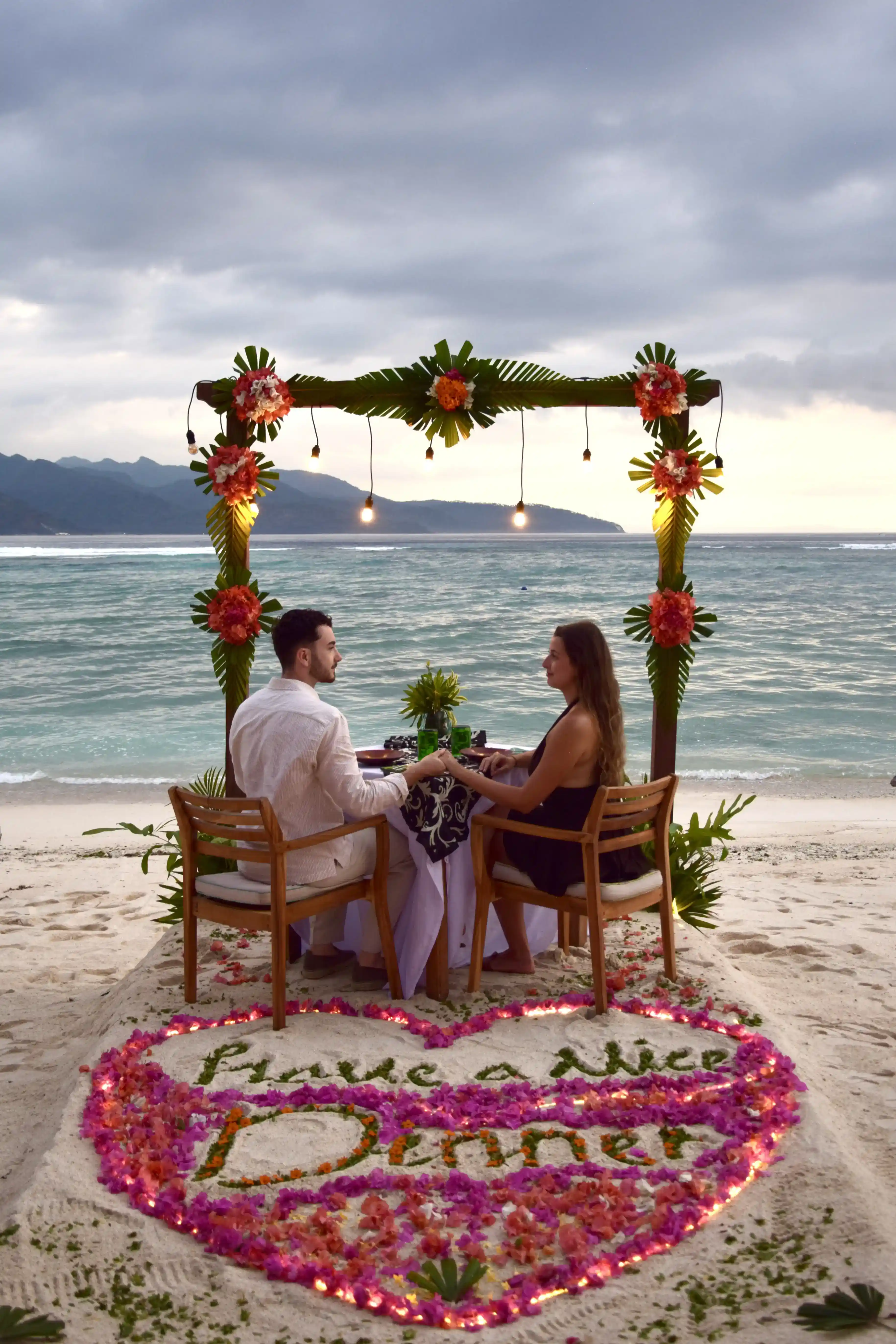 A romantic dinner at Santi Beach, Pondok Santi Estate, with a couple enjoying an evening by the beach.