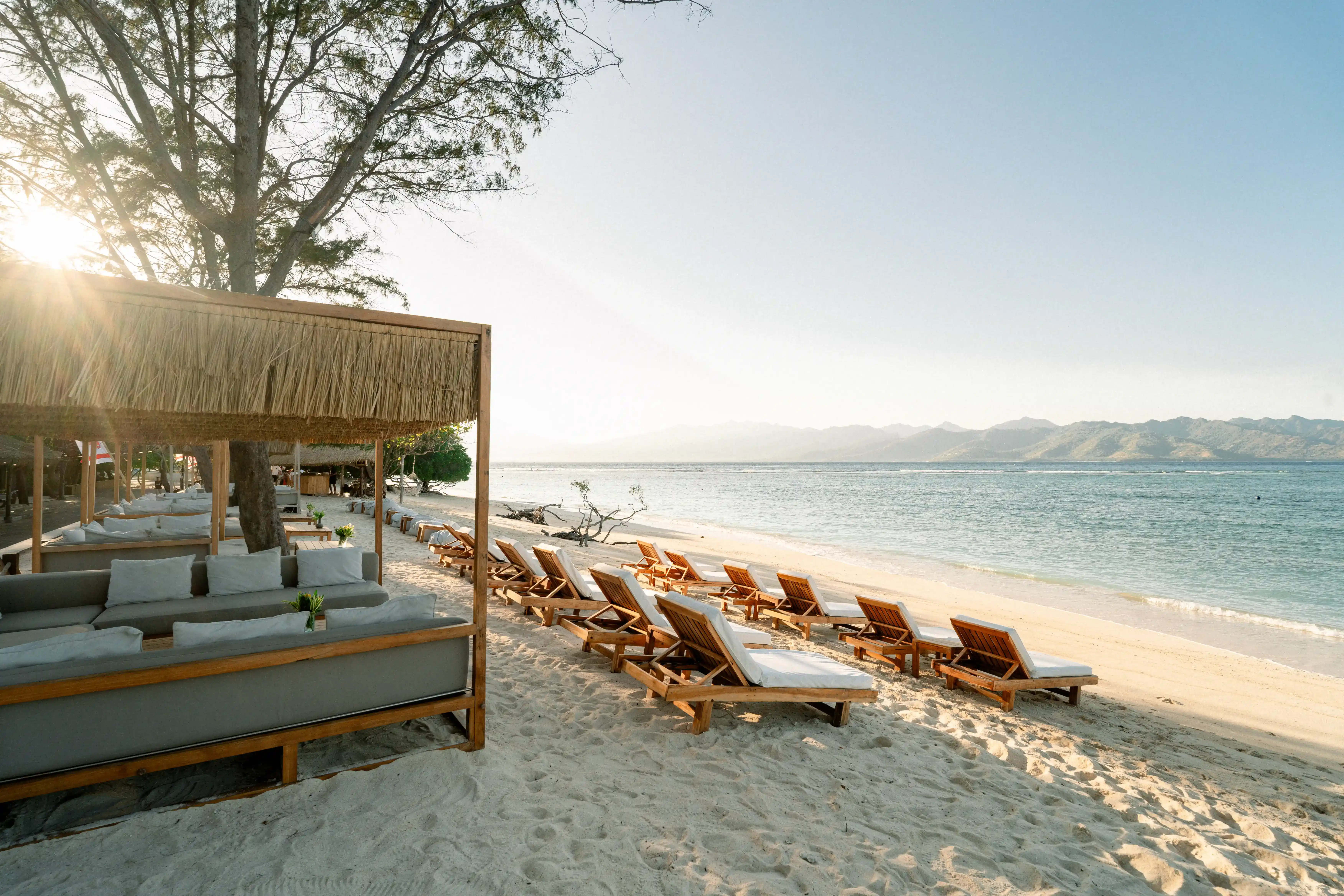 Santi Beach restaurant at Pondok Santi Estate, with cozy sofas and dining tables set on white sand beach overlooking clear waters.
