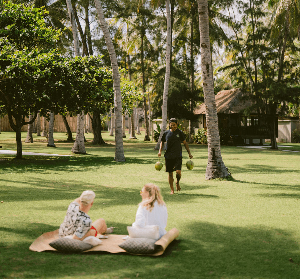 Santi Coco experience at Pondok Santi Estate, Gili Trawangan. Employee carrying fresh coconuts to guests.