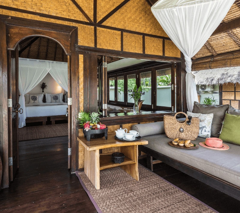 Terrace of a Palm View Bungalow at Pondok Santi Estate, Gili Trawangan, with a comfortable sofa and large windows allowing natural light.