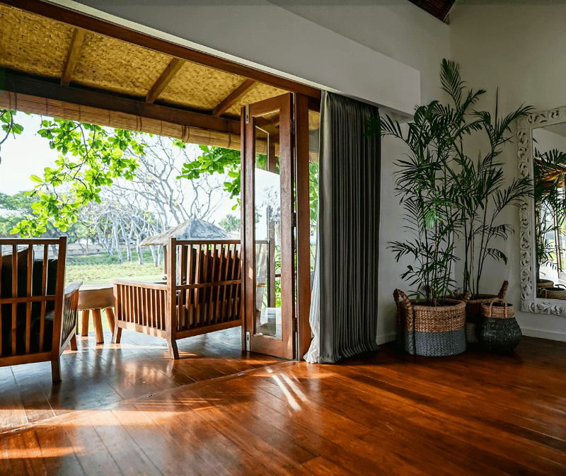 View from inside Ocean View Villa at Pondok Santi Estate, Gili Trawangan, showing a beautiful terrace seating area overlooking property grounds with the ocean in the background.
