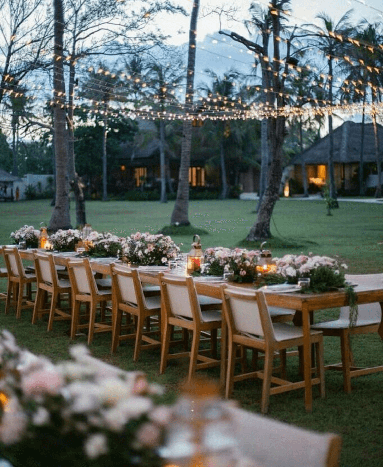 Long decorated tables at a wedding, with lights strung from trees and villas in the background at Pondok Santi Estate, Gili Trawangan.