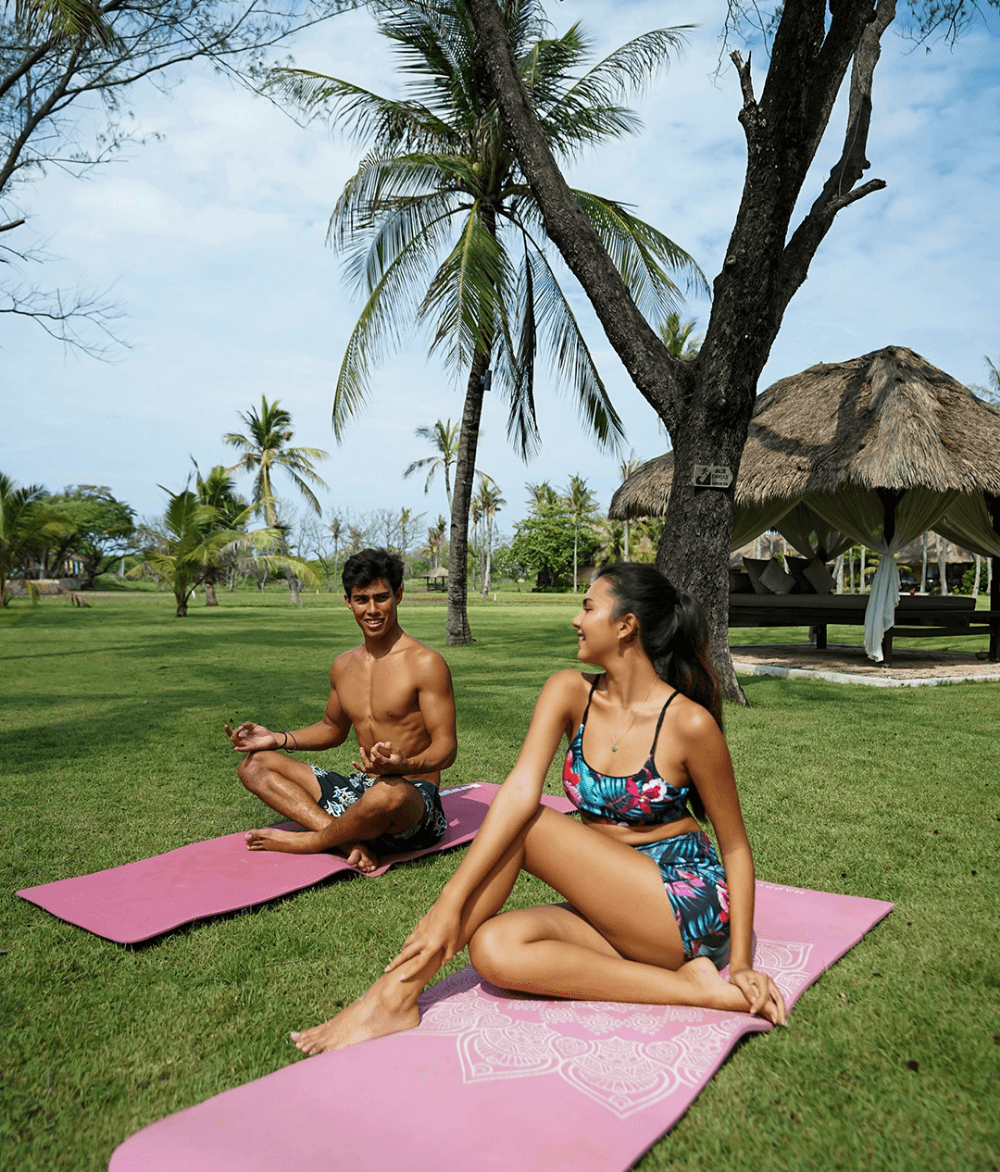 Couple practicing yoga amid coconut trees and lush plants at Pondok Santi Estate, Gili Trawangan.