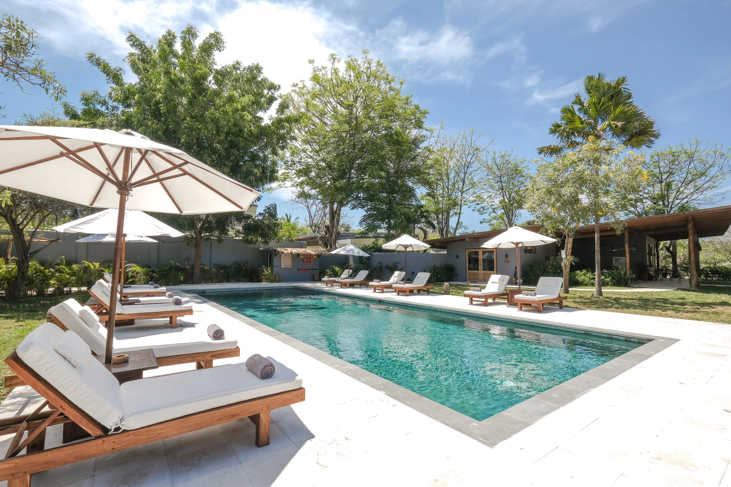 Exterior of the 2 Bedroom Lakeside Villa, showing the large covered terrace and wooden swing, surrounded by a private garden hover